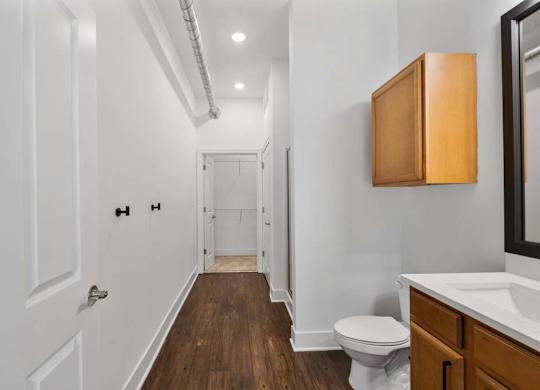 A white bathroom with wood floors and a white toilet.at The Foundry, South Bend