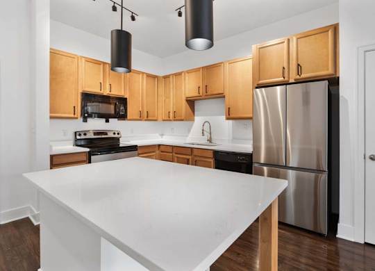 A kitchen with wooden cabinets and a white island.at The Foundry, South Bend, IN 46617