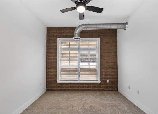 A room with a ceiling fan and a window with blinds.at The Foundry, South Bend Indiana
