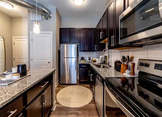 a kitchen with stainless steel appliances and granite counter tops at The Foundry, South Bend, IN 46617