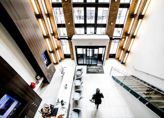 a woman walking through the lobby of a building at The Foundry, South Bend, 46617