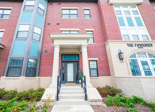 a red brick building with a glass door and steps in front of it at The Foundry, South Bend Indiana