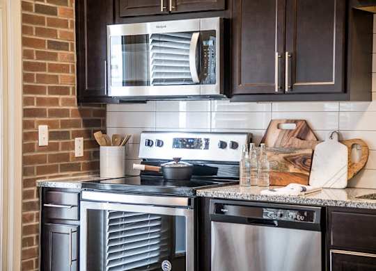 a kitchen with stainless steel appliances and black cabinets at The Foundry, South Bend, IN 46617