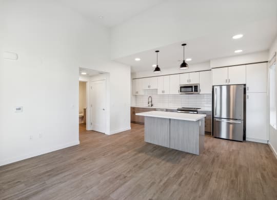 an empty living room with a kitchen with a stainless steel refrigerator at 38° NORTH, Santa Rosa, 95404 