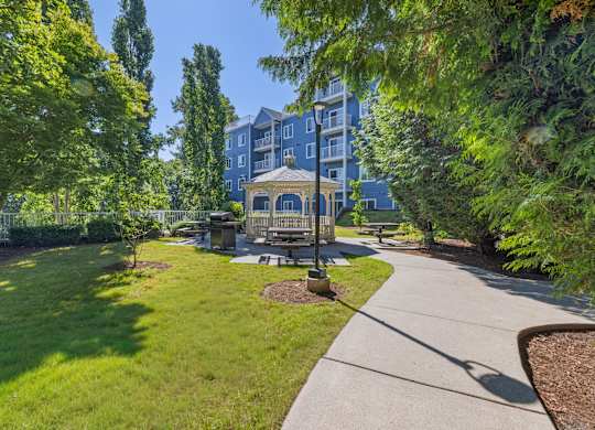 A park with a bench and a building in the background.