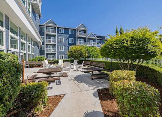 A courtyard with benches and a fence in front of apartment buildings.