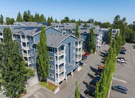 A parking lot in front of a row of apartment buildings.