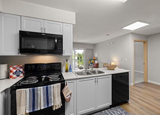 A kitchen with black appliances and white cabinets.
