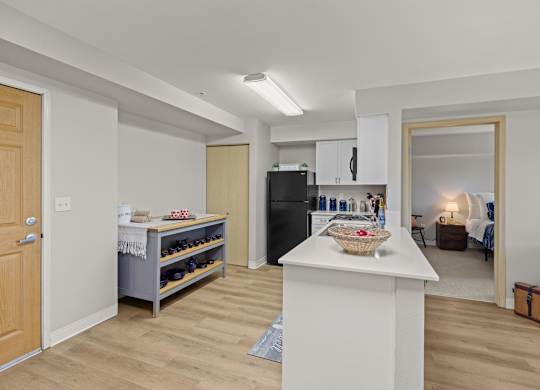 A kitchen with a white island and a black refrigerator.