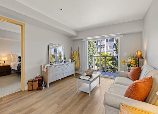 A well-lit, spacious living room with a large window and a view of a building outside.