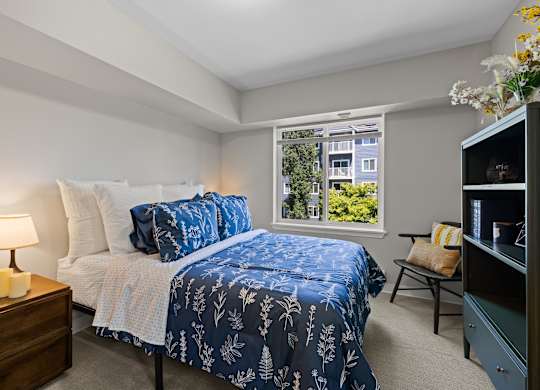 A bedroom with a bed and a window showing a view of a building.
