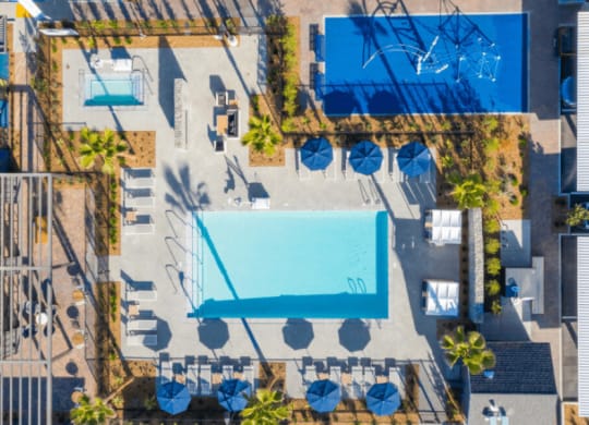 arial view of a resort pool with blue umbrellas and chairs