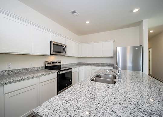 a kitchen with granite counter tops and a stainless steel refrigerator