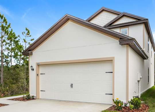Exterior of a two-story white house with a white garage door and brown trim.