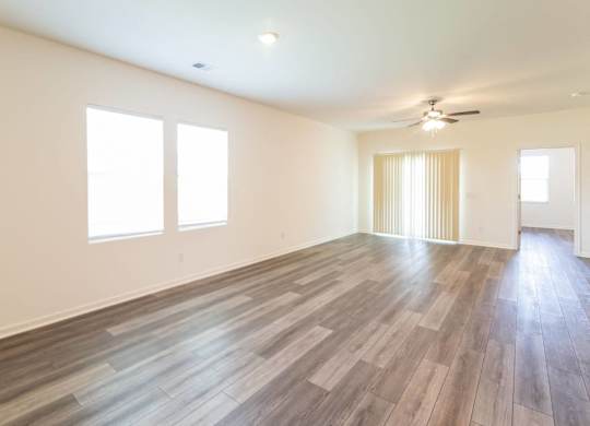 an empty living room with wood floors and a ceiling fan