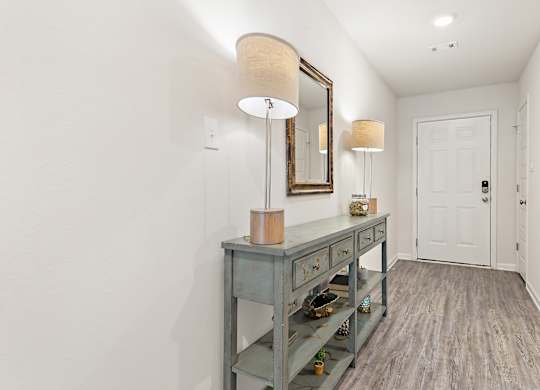 Entryway with blue console table, lamps, mirror, and wood-look flooring.