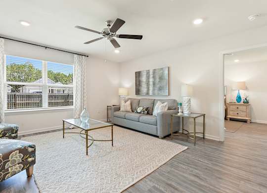 Bright, modern living room with gray sofa, floral accent chair, and glass coffee table.