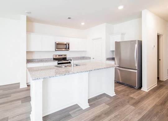 a kitchen with a marble counter top and a stainless steel refrigerator