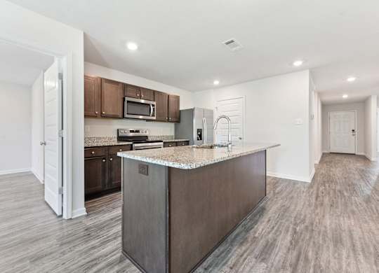 Modern kitchen with granite countertops, stainless steel appliances, and wood-look flooring.