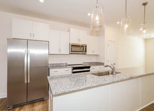 Townhouses for Rent in Charlotte, NC - Loso Walk - Modern Kitchen with Granite Countertops, a Kitchen Island, Hanging Lights, White Cabinetry, Stainless Steel Appliances, and Luxury Vinyl Plank Flooring