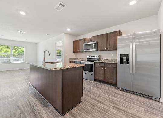 Modern kitchen with island, stainless steel appliances, and wood-look flooring.