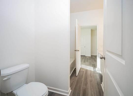 a white bathroom with a toilet and a hallway