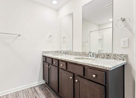 Bathroom with double sink vanity, granite countertop, and dark wood cabinets.