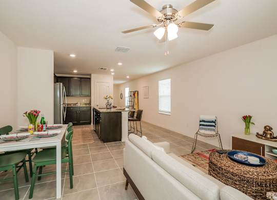 Open-concept living room and kitchen with dining table, island, and neutral decor.