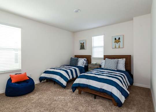 Bedroom with two twin beds, blue and white striped bedding, beanbag chair, and animal artwork.