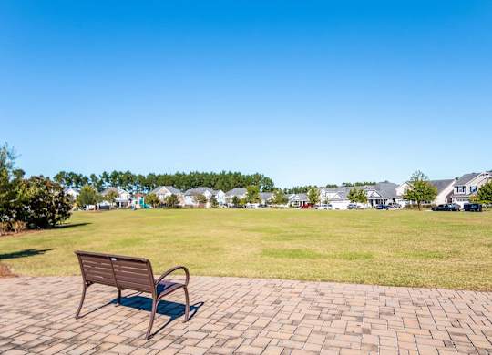a park bench on a brick sidewalk next to a grass field