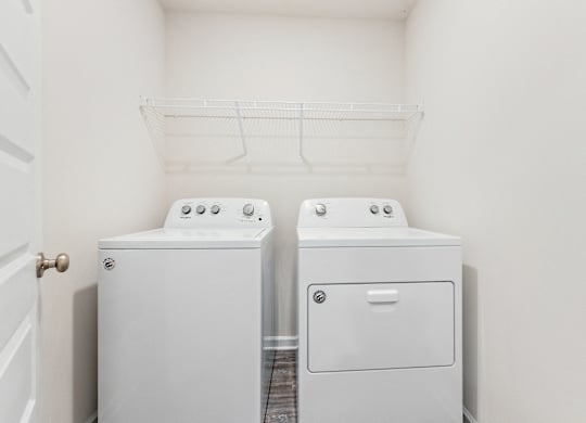 White Whirlpool washer and dryer in a laundry room with wire shelving.