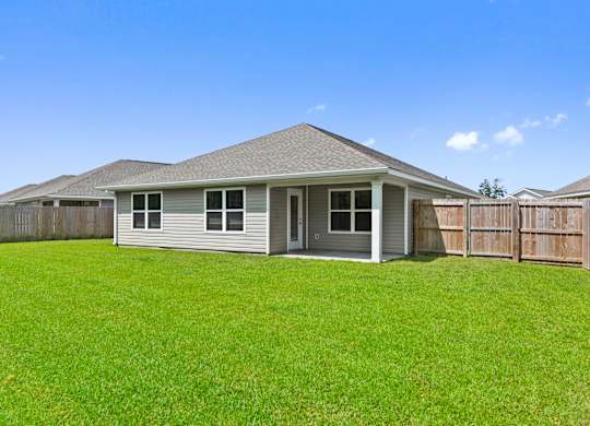 Backyard view of a single-story home with a covered patio and green lawn.