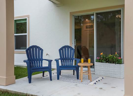 Blue Adirondack chairs on a porch with orange juice.
