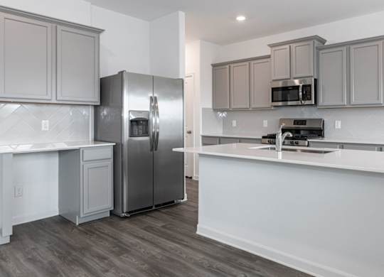 Humble, TX Apartments for Rent - Edgewater at the Lagoon - Kitchen with Stainless Steel Appliances, Gray Cabinetry, Large Kitchen Island, Quartz Countertops, and Hardwood Floor.