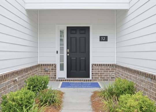 A black door with a glass window is on the right side of a white wall.