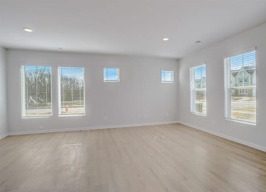 A large empty room with wooden floors and windows.
