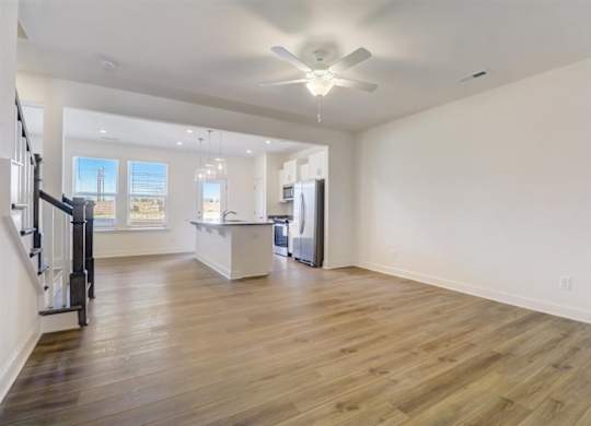 an empty living room with a kitchen in the background