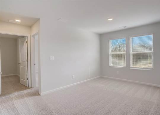A room with a carpeted floor and a window with blinds.
