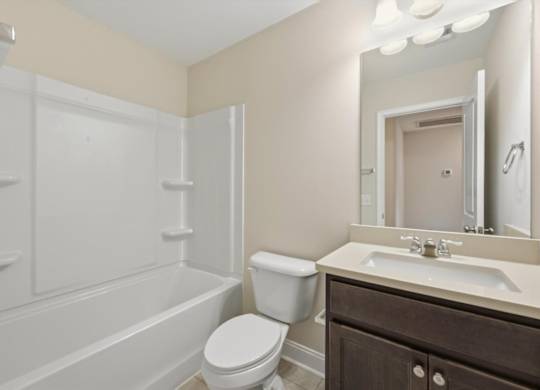 A white toilet sits next to a white bathtub in a bathroom.