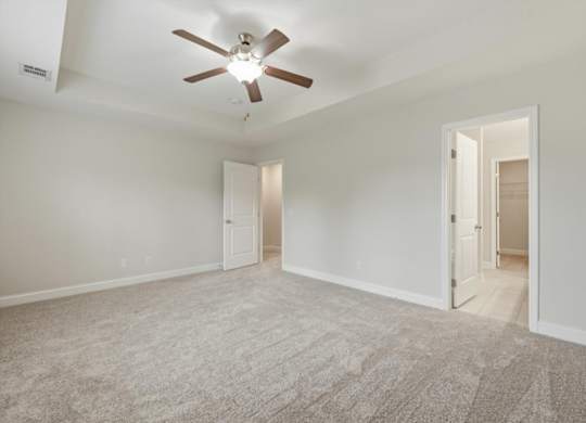 A room with a ceiling fan and carpeted floor.