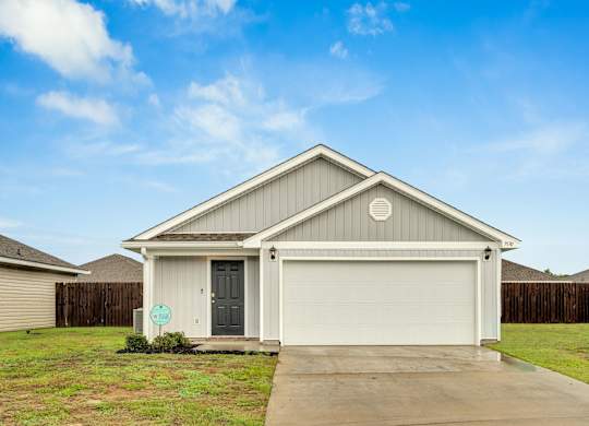 A house with a grey garage door and a green sign in front.