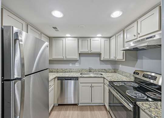 A modern kitchen with a stainless steel refrigerator and a granite countertop.