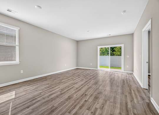A room with wooden flooring and a window with blinds.