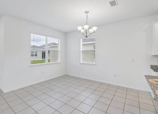 A room with white walls and a tiled floor with a chandelier hanging from the ceiling.
