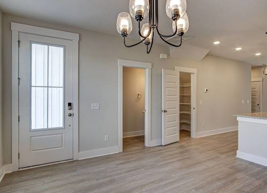 an empty living room with a door to a closet and a chandelier