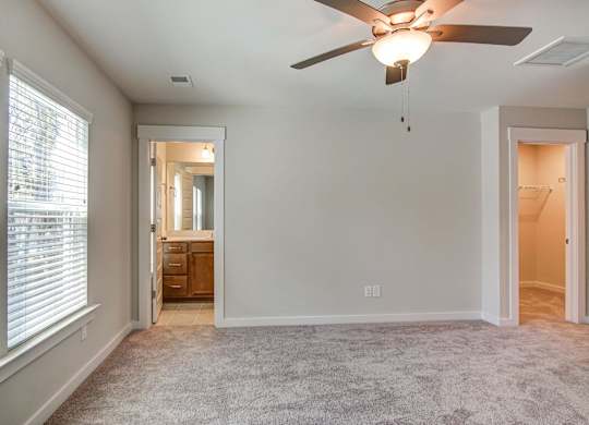 Dog-Friendly Homes for Rent in North Charleston, SC - Sumner Village - Bedroom with Plush Carpet Flooring, Ceiling Fan, Spacious Closet, Attached Bathroom, and Large Windows.