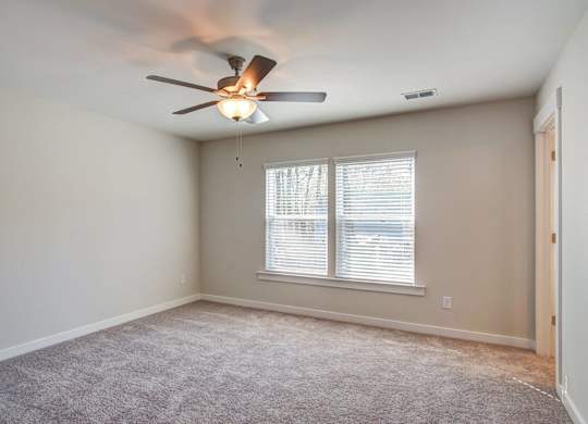 3-BR Homes In North Charleston, SC - Sumner Village - Spacious Bedroom With Carpet Flooring, Ceiling Fan, Large Window, And Access To The Bathroom