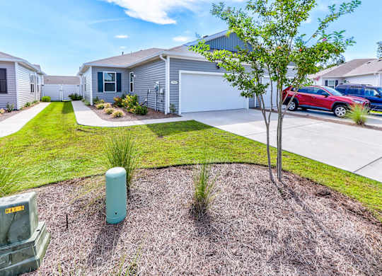 a house with a driveway and a tree in front of it
