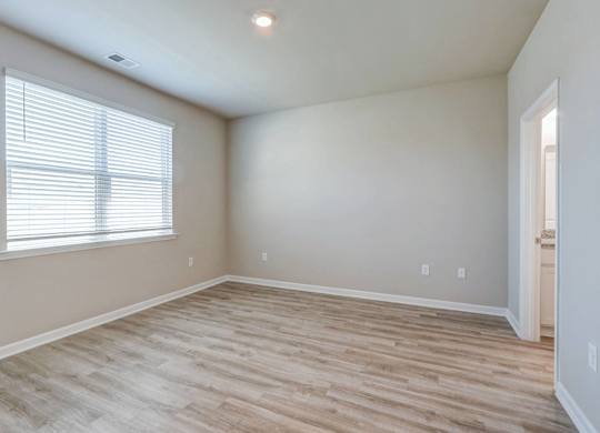 an empty living room with wood flooring and a window