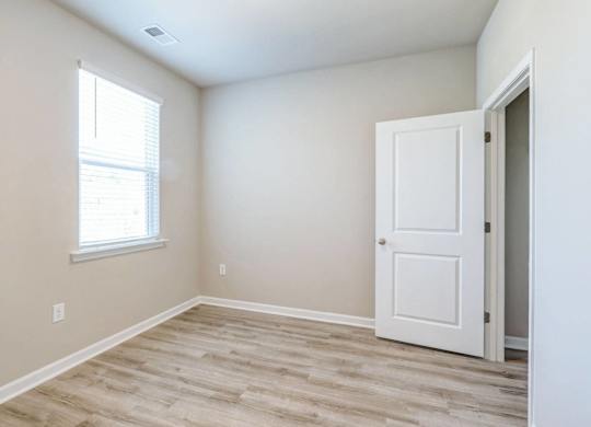 an empty room with a white door and a window